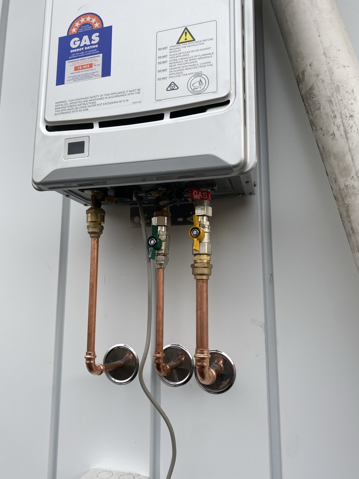Wall-mounted instantaneous gas hot water unit with copper pipework and isolation valves